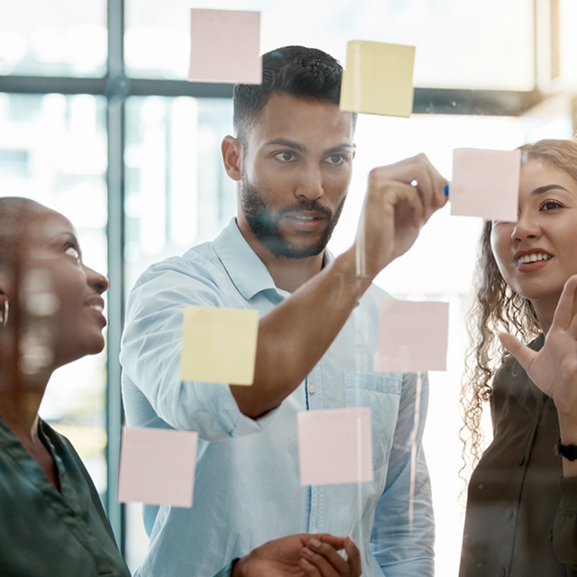 Team brainstorming with sticky notes on a glass wall